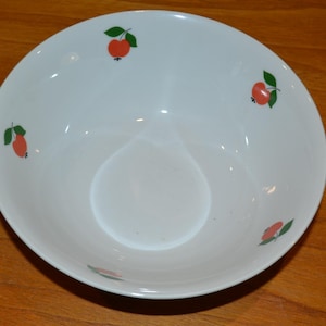 Pode incluir: Tigela de cerâmica branca com um design floral vermelho e verde. A tigela tem uma forma arredondada e um esmalte branco liso.