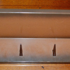 May include: A brown ceramic key holder with five hooks. The key holder is angled and has a light brown finish.