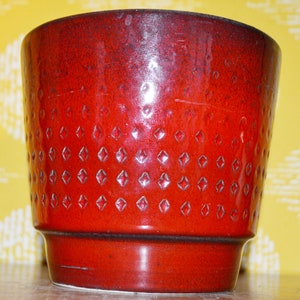 May include: A red ceramic planter with a diamond pattern. The planter has a glossy finish and is perfect for adding a touch of color to your home.
