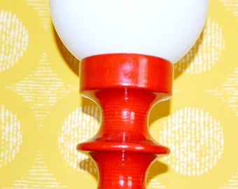May include: A red ceramic table lamp with a white globe shade. The lamp has a unique, hourglass-shaped base.