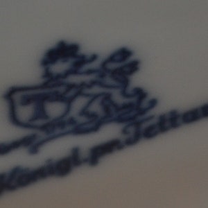 May include: A blue and white porcelain mark with the text "T. & J. Tettau" and a stylised image of a lion.