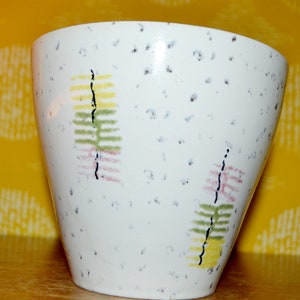 May include: White ceramic planter with a speckled glaze and abstract green, yellow, and pink designs.