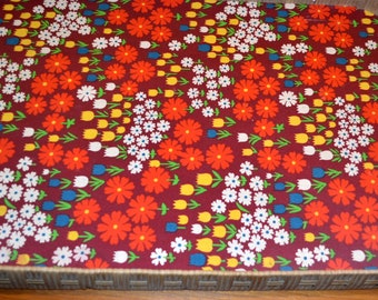 May include: A woven wicker tray with a floral pattern lining. The pattern features red, white, yellow, and blue flowers on a burgundy background.