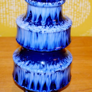 Puede incluir: Un jarrón de cerámica azul y blanco con un diseño en capas. El jarrón tiene un esmalte azul moteado con vetas blancas.