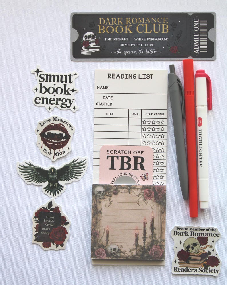 Op de afbeelding: Een verzameling briefpapier en stickers met een donker romantisch thema. Bevat een ticket, leeslijst, notitieblok, pennen en stickers met zinnen als "smut + book + energy" en "Love Monsters".