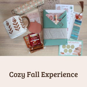 May include: A collection of items including a white mug with brown leaf patterns, a floral pencil case, a green wrapped package, a pumpkin-shaped notepad, Twinings tea bags, a reading list, a sticker sheet, and a fall watch list scratch-off card.
