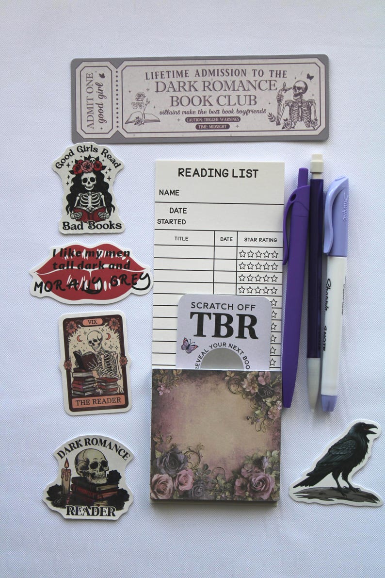 Op de afbeelding: Een verzameling briefpapierartikelen met een donker romantisch thema. Inclusief stickers met skelet- en ravenillustraties, een leeslijstnotitieblok, pennen en een kras-TBR-kaart. Het kleurenpalet is voornamelijk zwart, wit en paars.