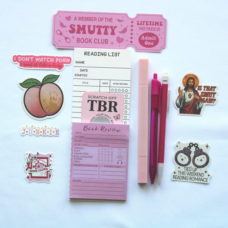 Op de afbeelding: Een verzameling roze briefpapier en stickers, waaronder een leeslijst, een notitieblok voor boekrecensies, pennen en stickers met zinnen als "I don't watch porn, I read it like a lady" en "Tied up this weekend reading romance."