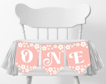 Op de afbeelding: Roze en witte hoge stoelbanner met het woord "ONE" in een wit cursief lettertype. De banner heeft aan elk uiteinde een witte kwast en een wit madeliefjespatroon.