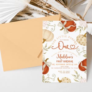 Fall-themed 1st birthday pumpkin digital invite with watercolor pumpkins, bows, and florals in blush, ivory, and burnt orange, displayed on a printed card and matching iPhone mockup.