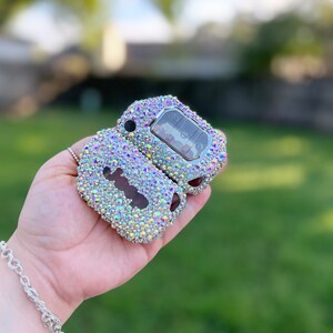 Pu&ograve; includere: Una custodia per telecomando per chiavi auto aperta, tempestata di strass iridescenti. La custodia della chiave mostra i pulsanti della chiave e la chiave stessa. Gli strass sono un mix di colori, tra cui rosa, giallo e blu.