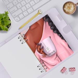 May include: A spiral-bound planner featuring an illustration of a person with dark skin and a long braid wearing a pink top. The person holds a light pink mug with the text Good Morning and the name Michelle printed on the side of the mug.