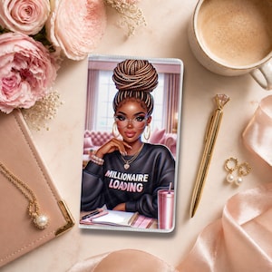 May include: A decorative phone case featuring an illustration of a woman with glasses and a high bun. She is wearing a black sweatshirt with the text "MILLIONAIRE LOADING". The case is surrounded by a pink notebook, flowers, a pen, and a cup of coffee.