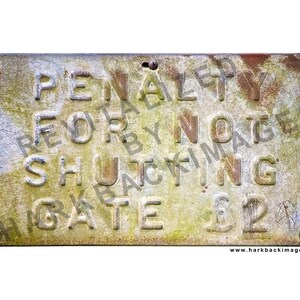May include: Weathered metal sign with embossed text: "PENALTY FOR NOT SHUTTING GATE $2". The sign is rectangular, with visible rust and green discoloration. Four screws secure the sign to a surface.