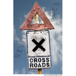 May include: Weathered railroad crossing sign with a faded red triangle above a white sign with a black cross. The sign reads "CROSS ROADS" in black lettering. The sky is blue with white clouds.