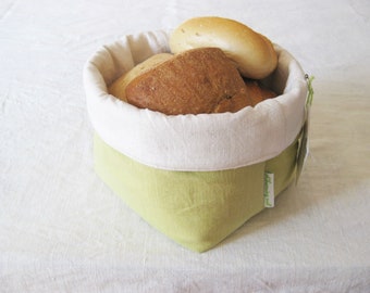 Op de afbeelding: Een groene en witte stoffen broodmand met een witte linnen voering. De mand is gevuld met verschillende broden.