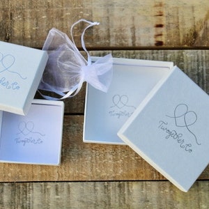 May include: Three white gift boxes with the text "Together Co." and a stylized heart design. The boxes are on a wooden surface.