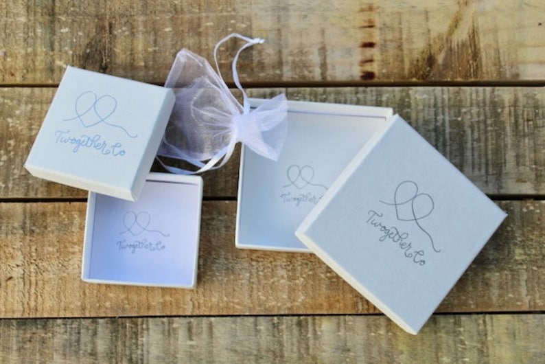 May include: Three white gift boxes with the text "Together Co." and a stylized heart design. The boxes are on a wooden surface.