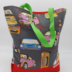 Könnte beinhalten: Eine graue und rote Einkaufstasche mit einem grünen Griff. Die Tasche ist aus Stoff und hat ein Patchwork-Design mit bunten Mini-Cooper-Autos.