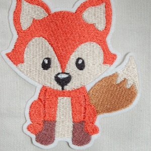 Könnte beinhalten: Gestickter Aufnäher mit einem Cartoon-Fuchs. Der Fuchs hat orangefarbenes Fell, ein weißes Gesicht und eine weiße Brust sowie einen braunen Schwanz. Der Aufnäher ist weiß umrandet und ist für Kleidung oder Accessoires bestimmt.