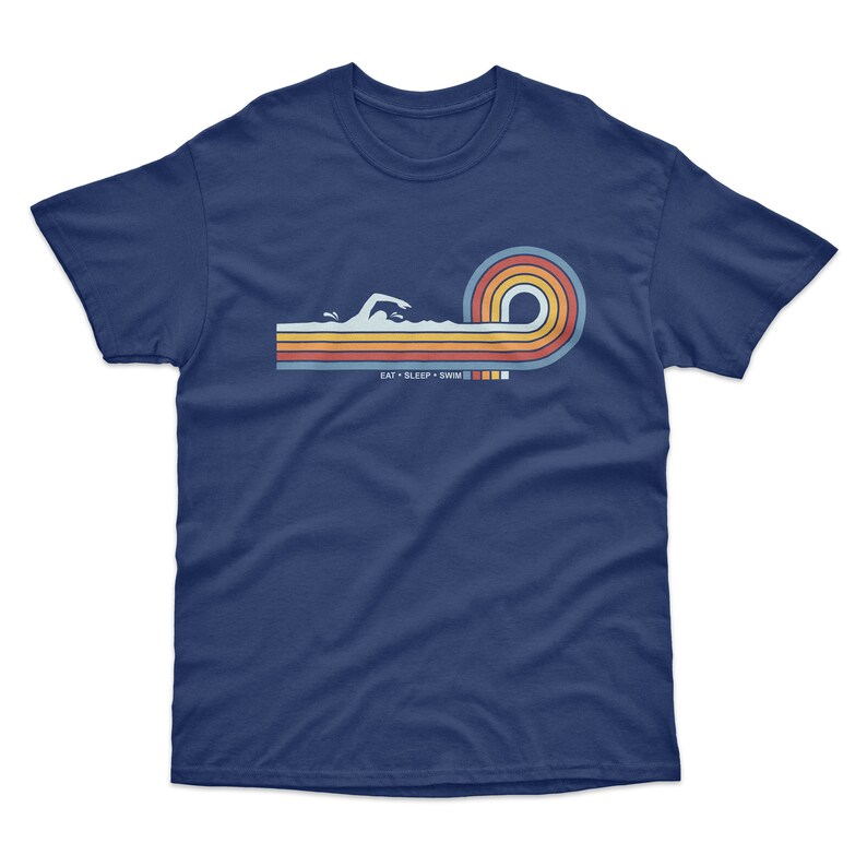 May include: Navy blue t-shirt with a retro-style graphic of a swimmer in a wave of colorful stripes. The text "EAT SLEEP SWIM" is printed below the graphic.