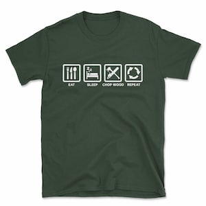 May include: A dark green t-shirt with a white graphic design. The graphic shows four icons in a row: a fork and knife, a bed with Zzz's above it, a chainsaw with an axe, and a circular arrow. The text below the icons reads "Eat, Sleep, Chop Wood, Repeat."