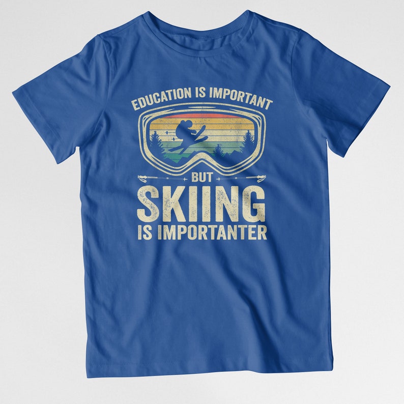 May include: Blue t-shirt with a vintage-style graphic of a skier wearing goggles. The text reads "Education is important, but skiing is importanter."