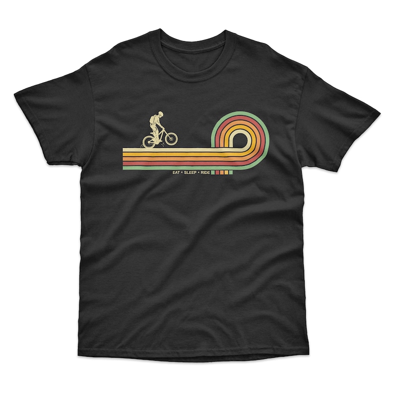 May include: Black t-shirt with a retro-style graphic of a person riding a bicycle on a rainbow-colored path. The text "EAT - SLEEP - RIDE" is below the graphic.