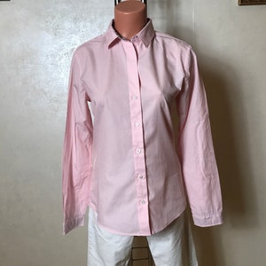 Peut inclure: Une chemise à manches longues boutonnée de couleur rose pâle avec des boutons blancs.