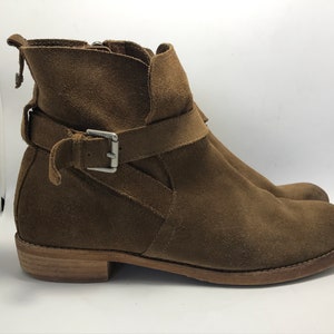 May include: Brown suede ankle boots with a buckle strap and a wooden heel.