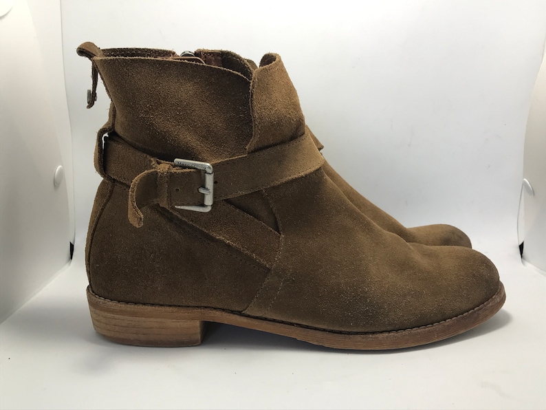 May include: Brown suede ankle boots with a buckle strap and a wooden heel.