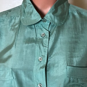 Op de afbeelding: Een groen zijden overhemd met een peter pan kraag. Het overhemd heeft een enkele borstzak en een knoopsluiting.