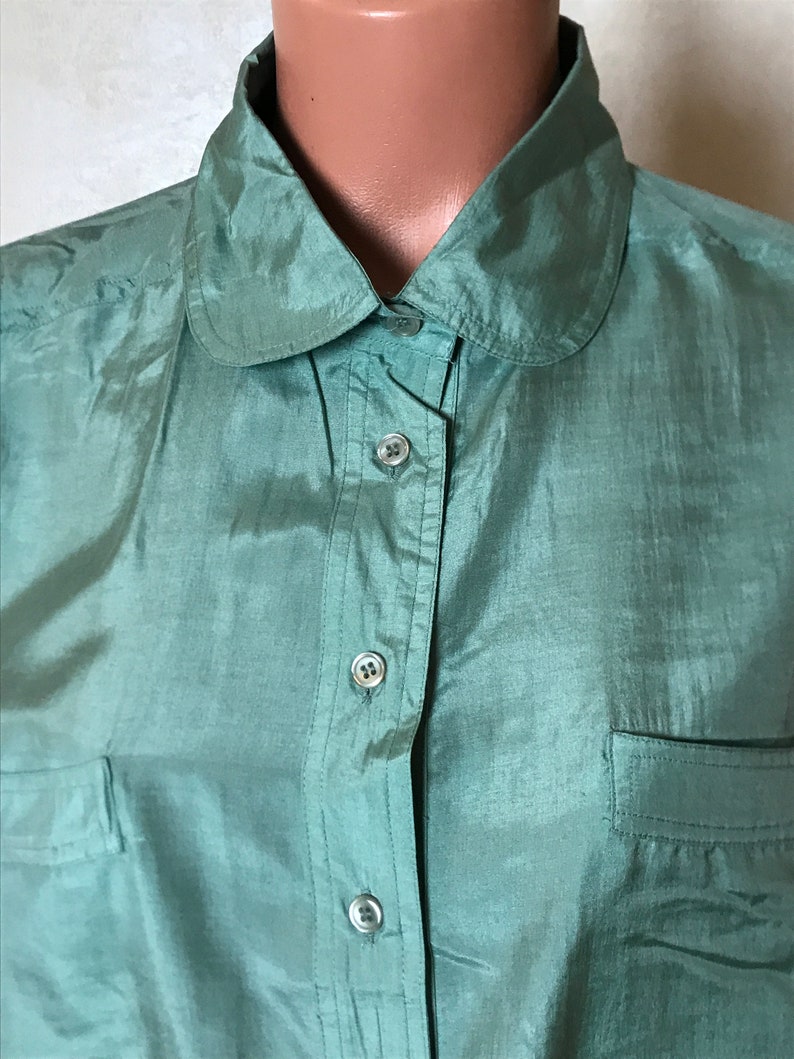 Op de afbeelding: Een groen zijden overhemd met een peter pan kraag. Het overhemd heeft een enkele borstzak en een knoopsluiting.