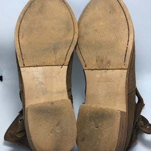 May include: A pair of brown suede ankle boots with a lace-up design and a low heel. The boots are size 5.