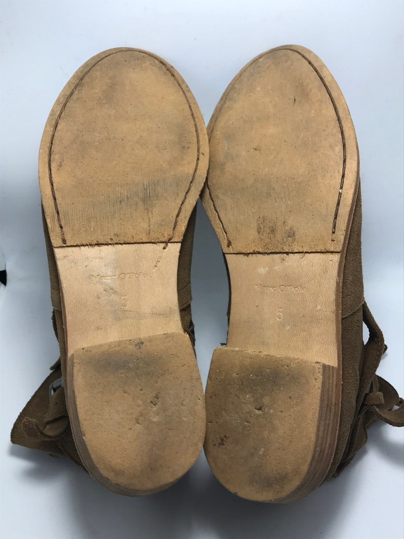 May include: A pair of brown suede ankle boots with a lace-up design and a low heel. The boots are size 5.