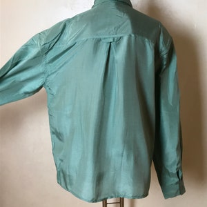 Op de afbeelding: Een lang mouw, lichtgroen overhemd met een knoopsluiting. Het overhemd is gemaakt van een zijdeachtig materiaal en heeft een gladde, glanzende afwerking.