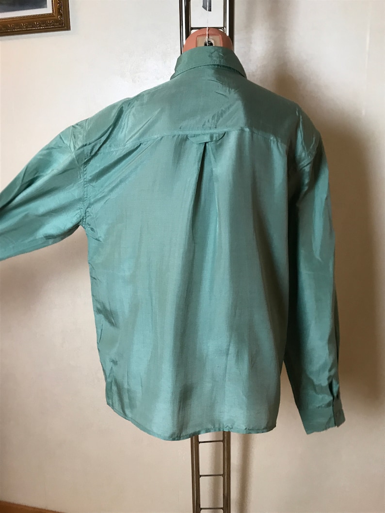 Op de afbeelding: Een lang mouw, lichtgroen overhemd met een knoopsluiting. Het overhemd is gemaakt van een zijdeachtig materiaal en heeft een gladde, glanzende afwerking.