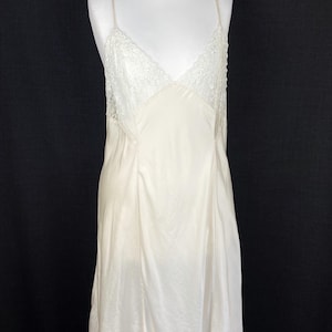 May include: A white satin slip dress with lace trim. The dress has a V-neckline and thin straps.