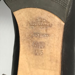 May include: Close-up of the sole of a black leather shoe with the brand name "Giovanni Galiano" and the size "6 1/2 EU 9 US" printed on the insole.