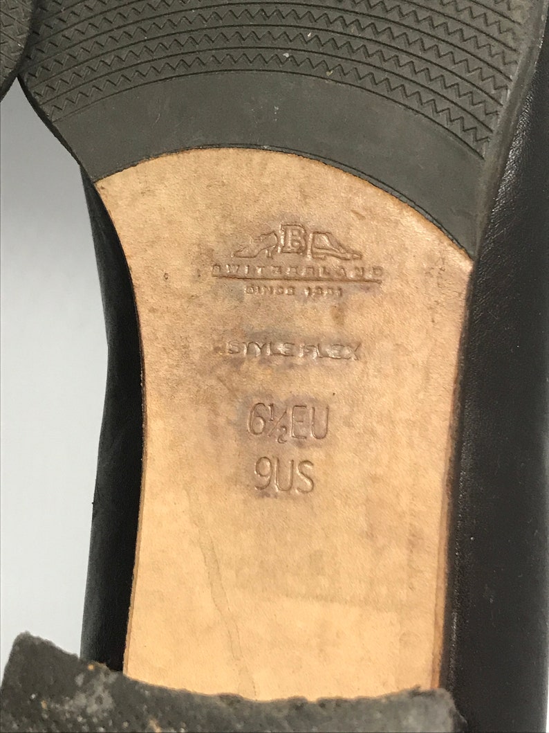 May include: Close-up of the sole of a black leather shoe with the brand name "Giovanni Galiano" and the size "6 1/2 EU 9 US" printed on the insole.