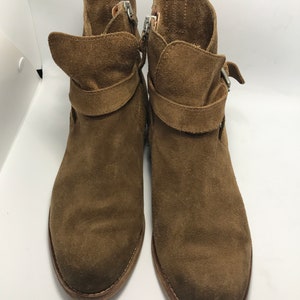 May include: A pair of brown suede ankle boots with buckle accents and side zippers.