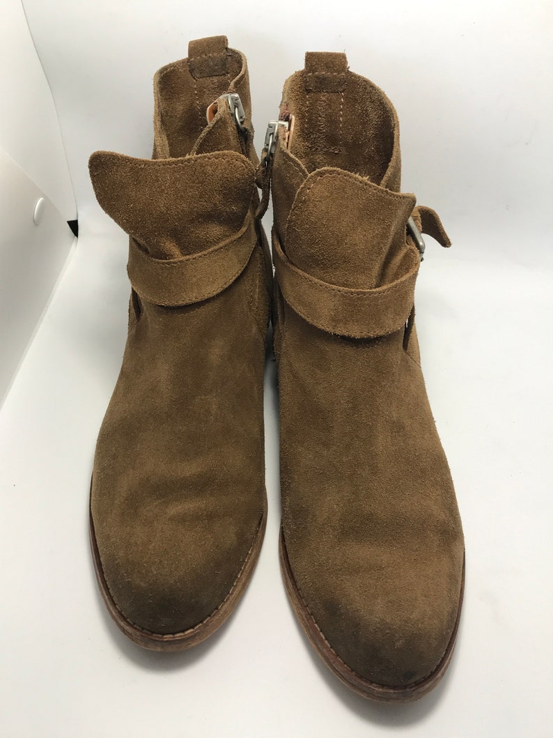 May include: A pair of brown suede ankle boots with buckle accents and side zippers.