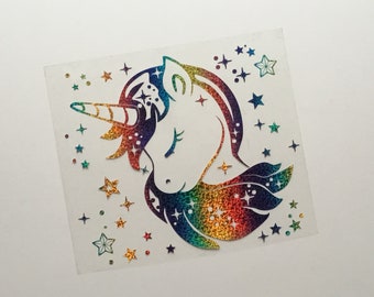 May include: A holographic unicorn sticker with a rainbow mane, horn, and body. The unicorn is surrounded by star-shaped and dot-shaped embellishments. The sticker has a glittery, iridescent finish, creating a shimmering effect.