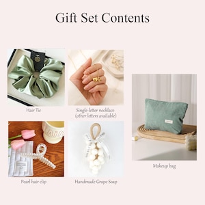 May include: A gift set with various items, including a green satin hair tie, a single-letter necklace, a pearl hair clip, a handmade grape soap, and a green corduroy makeup bag. The text "Gift Set Contents" is at the top.