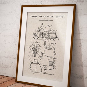 May include: A black and white line drawing of a motorcycle saddle carrier patent. The patent drawing shows a motorcycle with a saddle carrier attached to the back. The drawing includes multiple views of the saddle carrier, showing its design and features. The patent number is 2,857,412 and the inventor is Conrad La Rochelle.