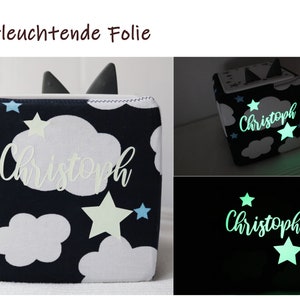 May include: A dark blue fabric cube with white clouds and stars. The stars glow in the dark. The cube is personalized with the name "Christoph".