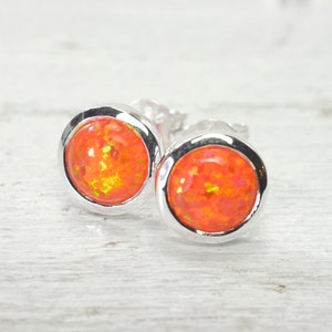 Könnte beinhalten: Ein Paar silberne Ohrstecker mit orangefarbenen Opalen.