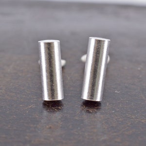 May include: A pair of silver bar stud earrings. The earrings are simple and sleek, with a polished finish.
