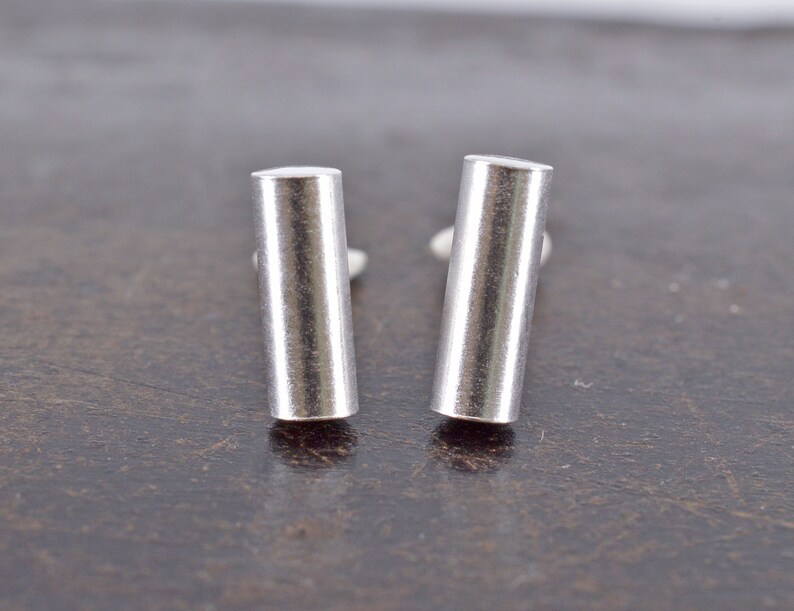 May include: A pair of silver bar stud earrings. The earrings are simple and sleek, with a polished finish.