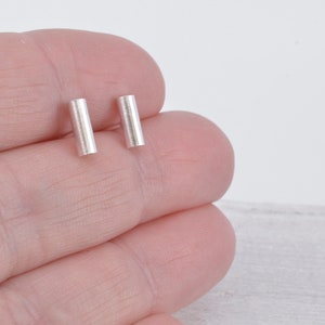 May include: A pair of silver bar stud earrings. The earrings are simple and minimalist, and they are perfect for everyday wear.